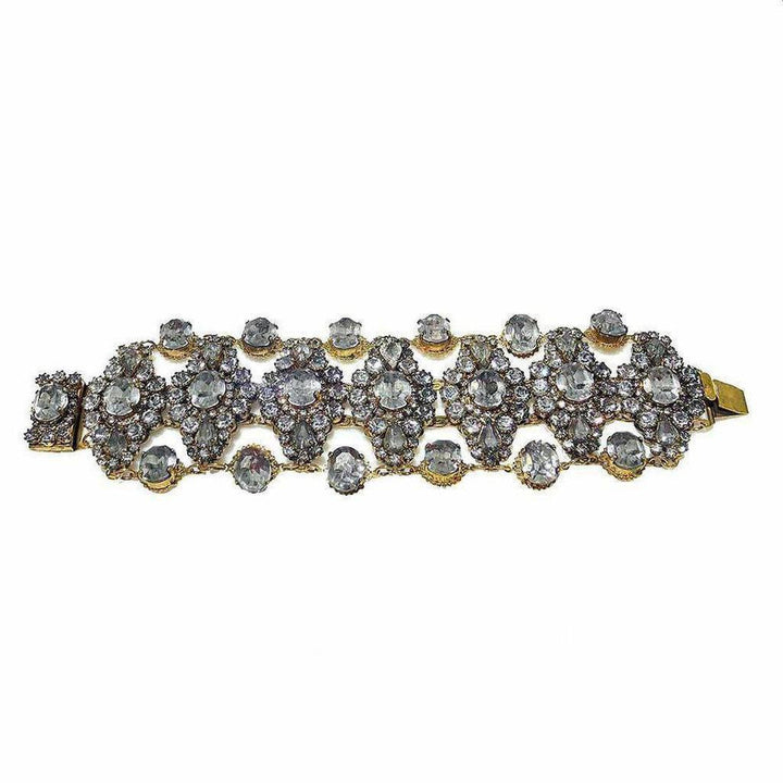 Gold bracelet adorned with sparkling clear stones, arranged in an intricate floral pattern.