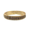 Gold hinged bangle bracelet with dark crystal accents.