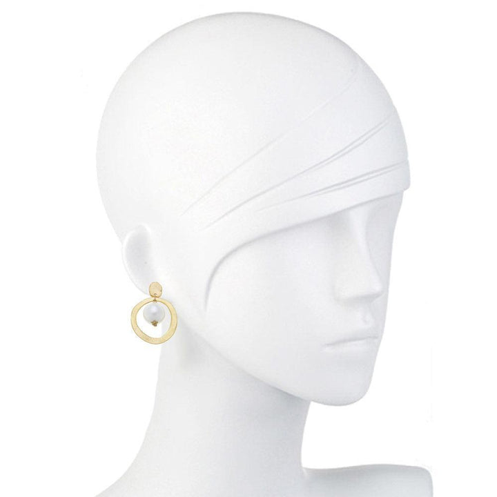 Gold hoop earrings featuring a single pearl; displayed on a mannequin.