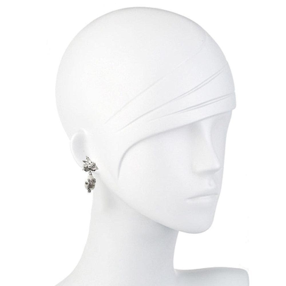 Elegant pearl drop earrings on a white mannequin, showcasing sparkling detail.