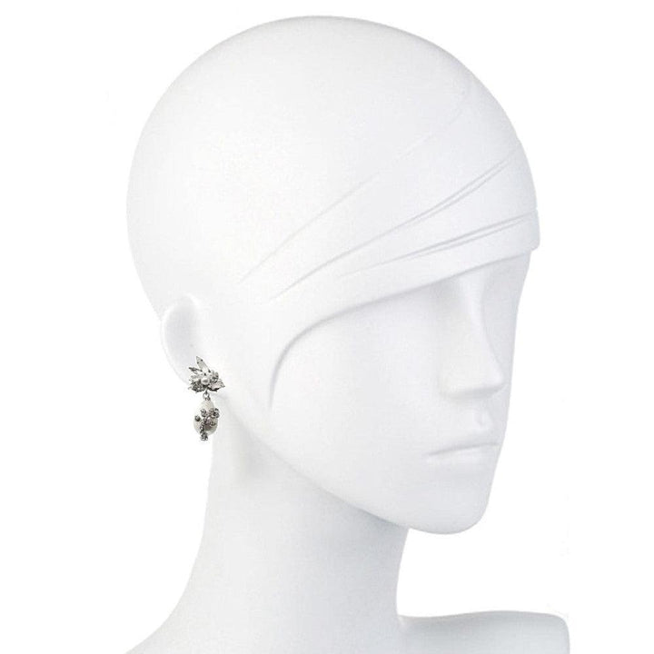 Elegant pearl drop earrings on a white mannequin, showcasing sparkling detail.