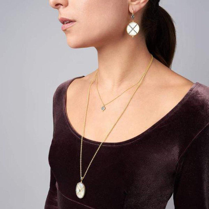 Oval mother-of-pearl pendant necklace with gold chain, worn with matching earrings.