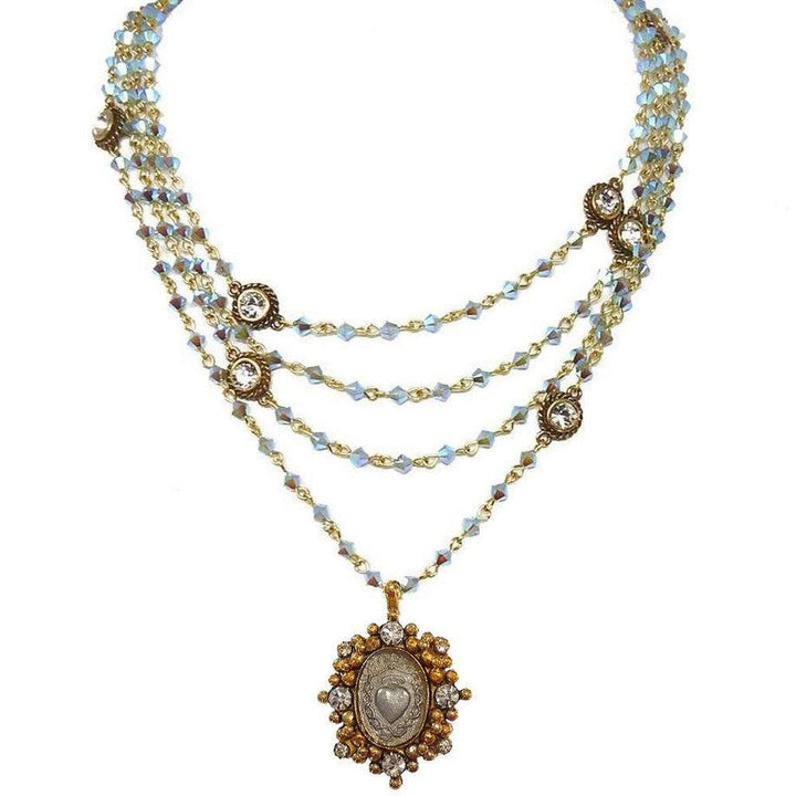 Layered iridescent blue crystal necklace with antique gold accents and a heart charm pendant.