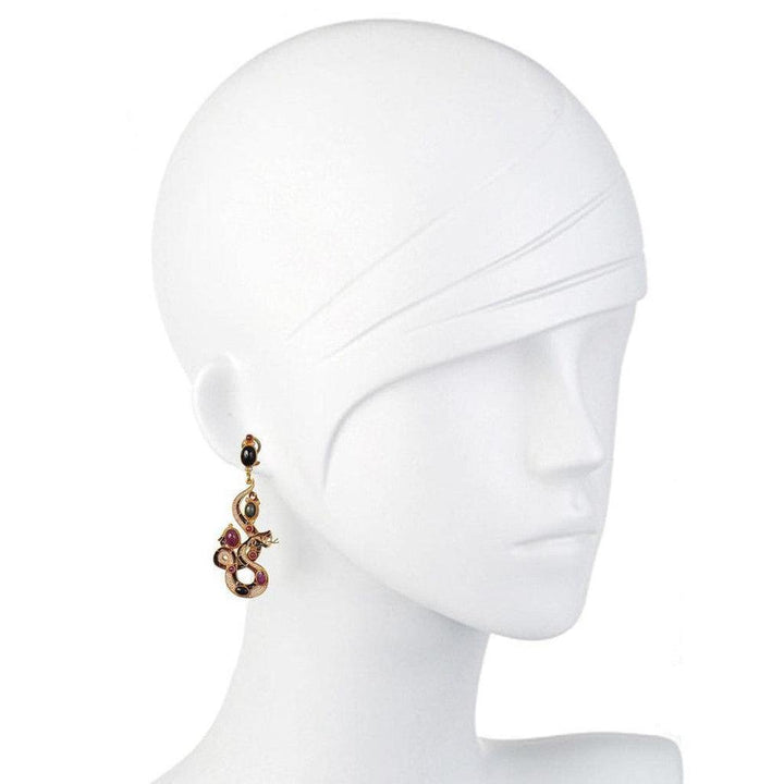Gold snake earrings with ruby and black gemstones, displayed on a mannequin.