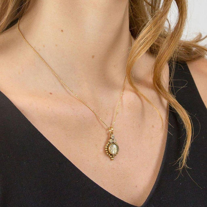 Gold chain necklace with ornate pendant featuring a clear gemstone.