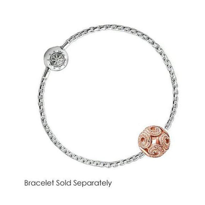 Rose gold charm featuring an intricate swirl design, on a silver chain; bracelet sold separately.