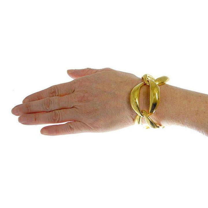 Gold link bracelet on a wrist, showcasing its large, sculpted design.