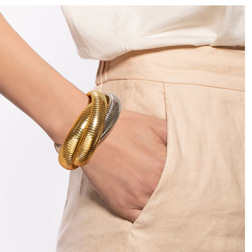 Triple-wrap gold and silver bracelet on a wrist, close-up.