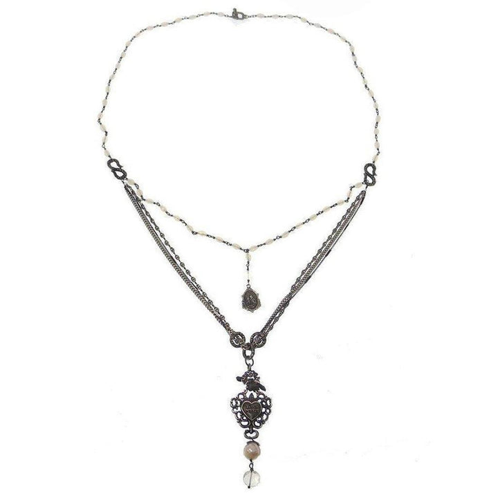Layered necklace featuring pearl beads, metal chains, and ornate heart pendant.