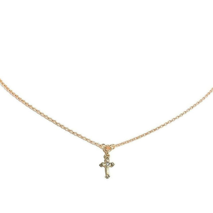 Dainty gold chain necklace with a small, ornate cross pendant.