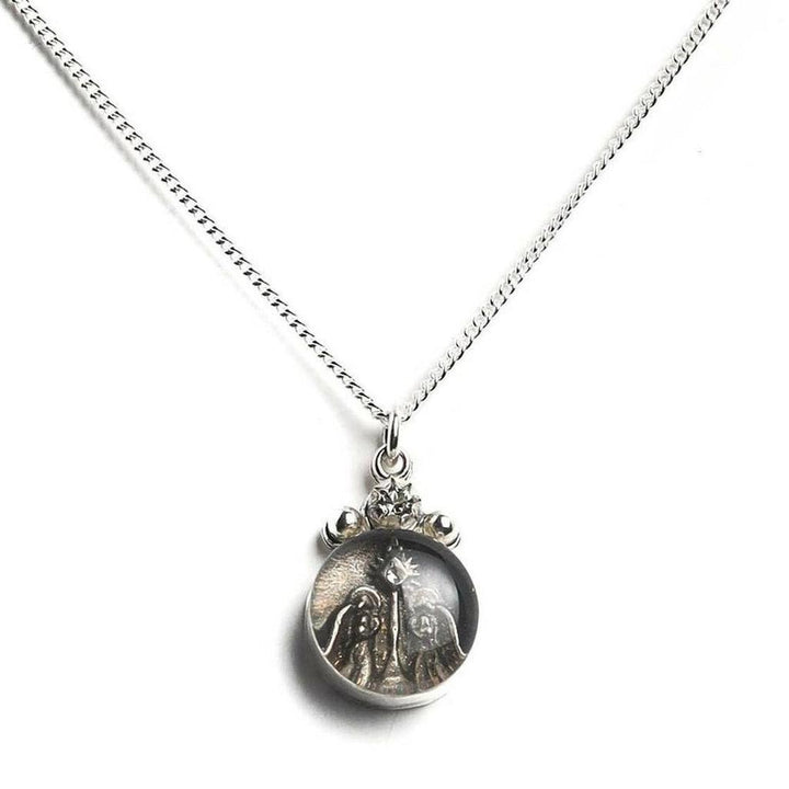 Silver chain necklace with circular nativity scene charm.