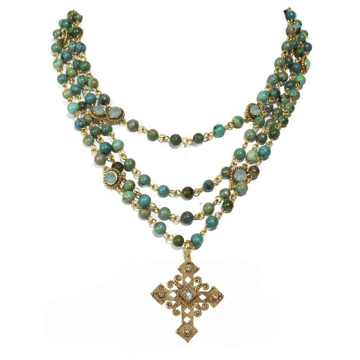Three-strand turquoise bead necklace with gold accents and ornate cross pendant.