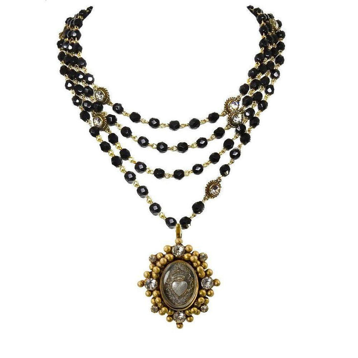 Layered black beaded necklace with gold accents and a detailed heart pendant.