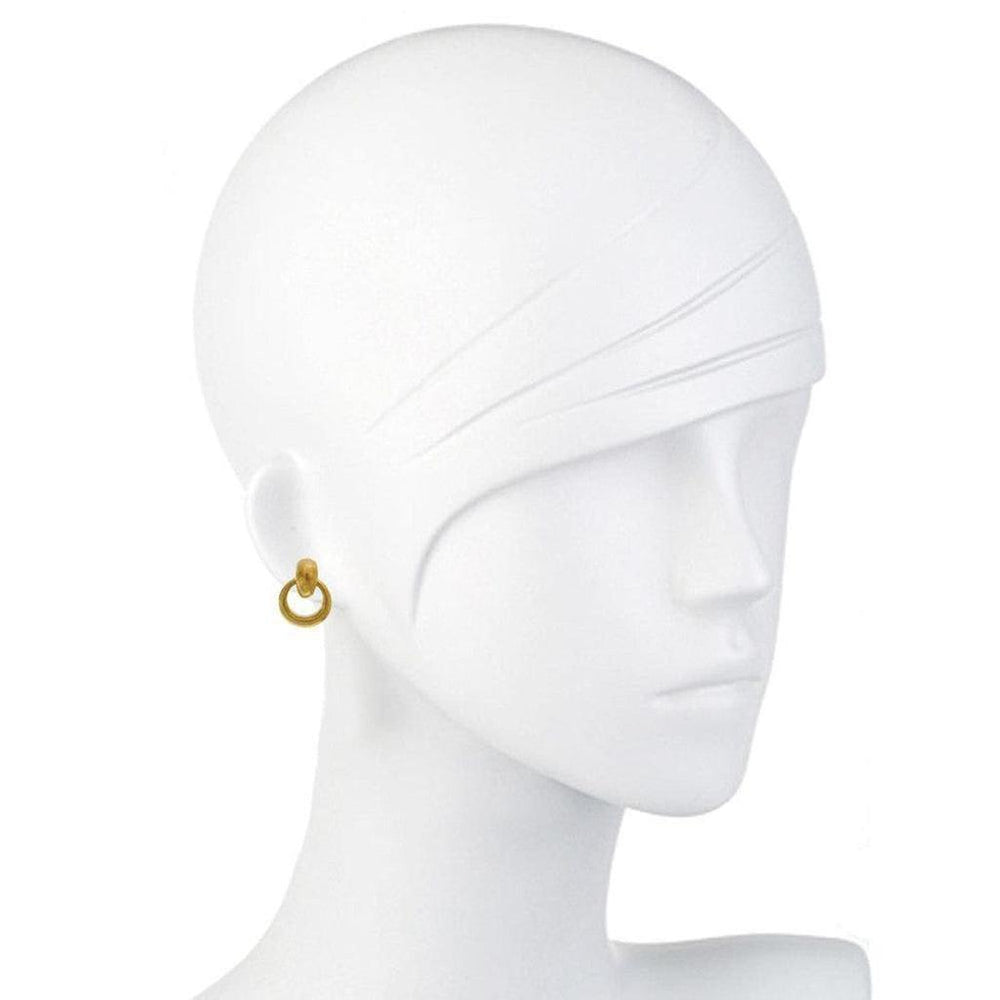 Gold doorknocker-style earrings on a mannequin, showcasing minimalist design.