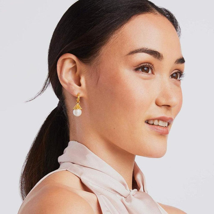 Gold hoop earrings featuring a single pearl drop, worn by a woman with a side profile.