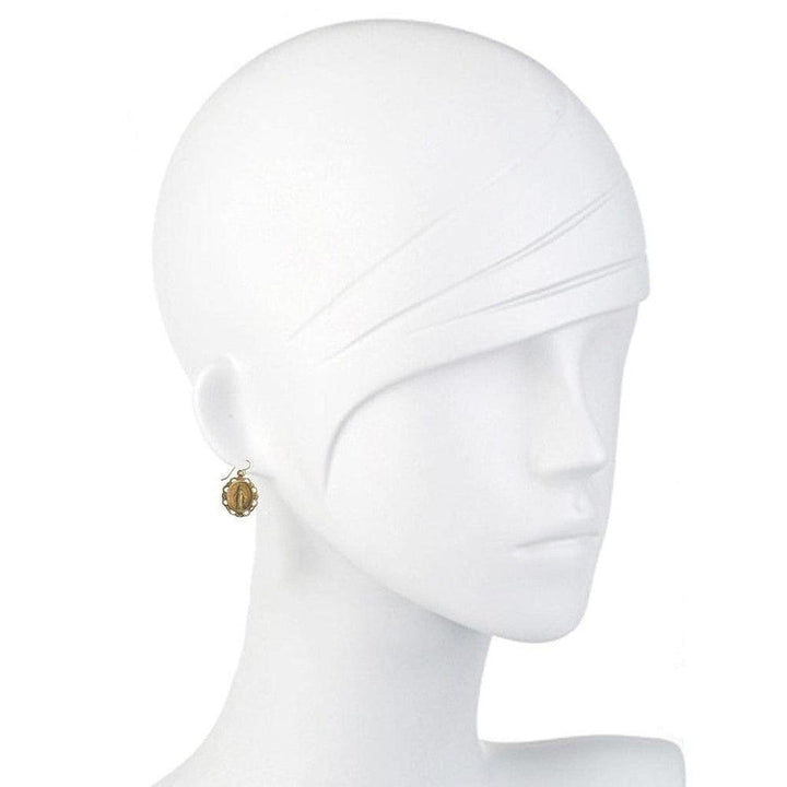 Gold oval earrings on a mannequin, showcasing delicate detail.