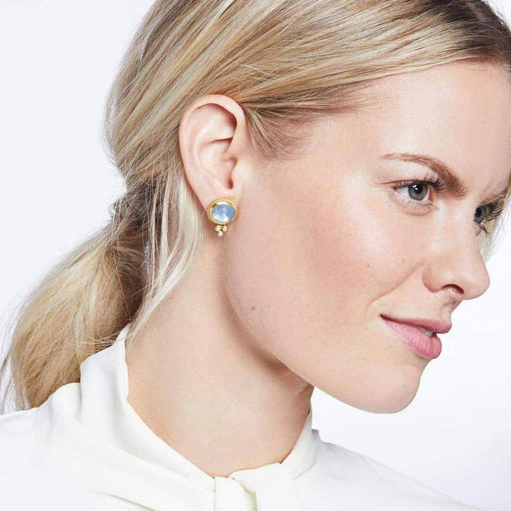 Gold stud earrings featuring a light blue gemstone and small pearl accents.