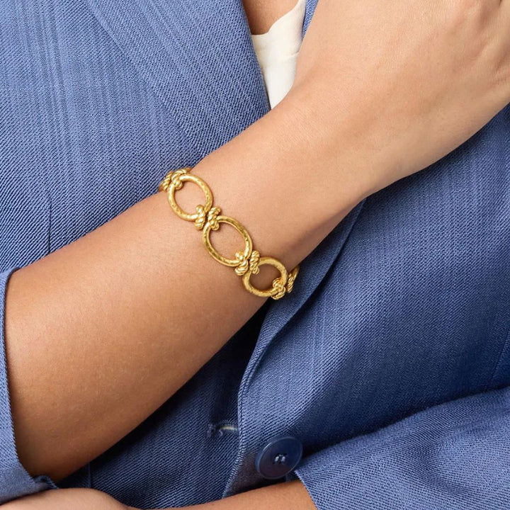 Gold link bracelet with twisted detailing, worn on a wrist.
