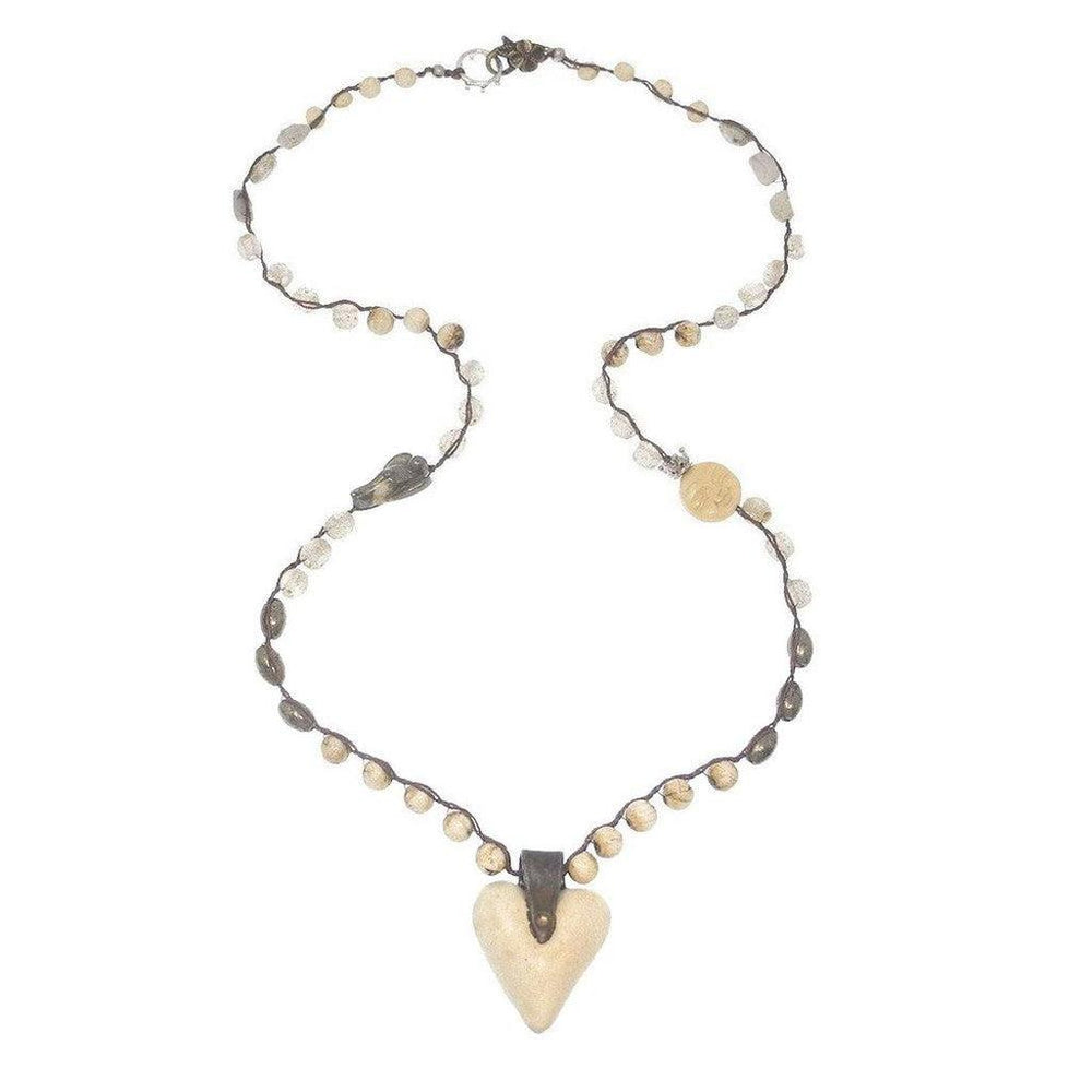 Beaded necklace with off-white heart pendant; features varying neutral-toned beads and brown cord.