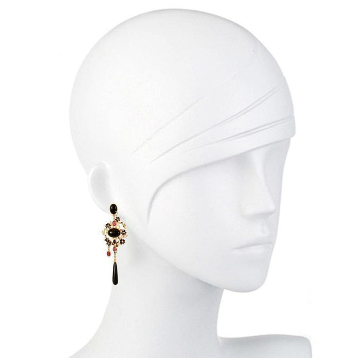 Gold drop earrings with black and red gemstones, displayed on a mannequin.