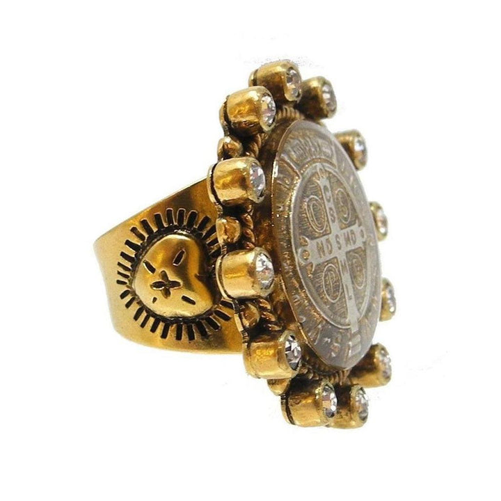 Gold statement ring featuring a detailed religious medallion, accented with clear stones.