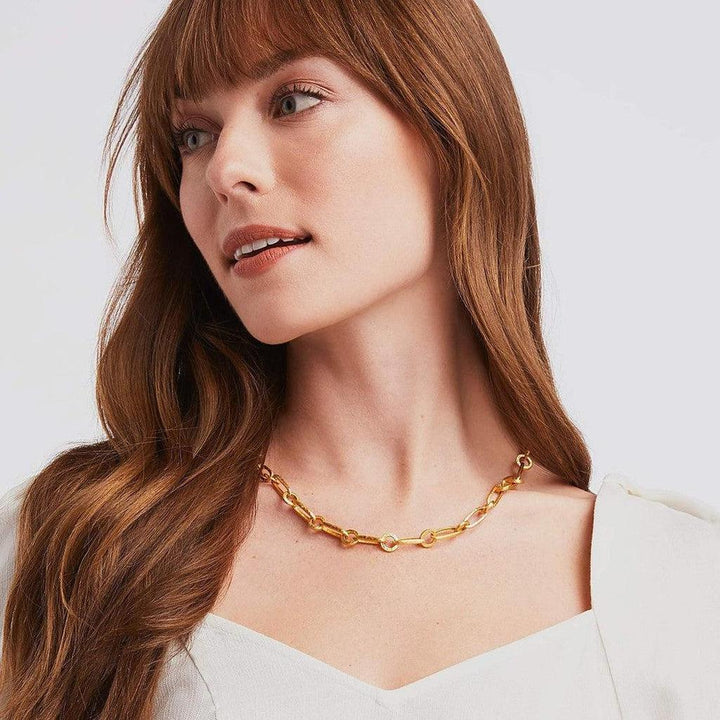 Woman with auburn hair wearing a gold link necklace.