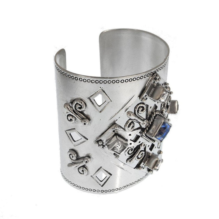 Wide silver cuff bracelet with ornate detailing, featuring blue and clear gemstones.