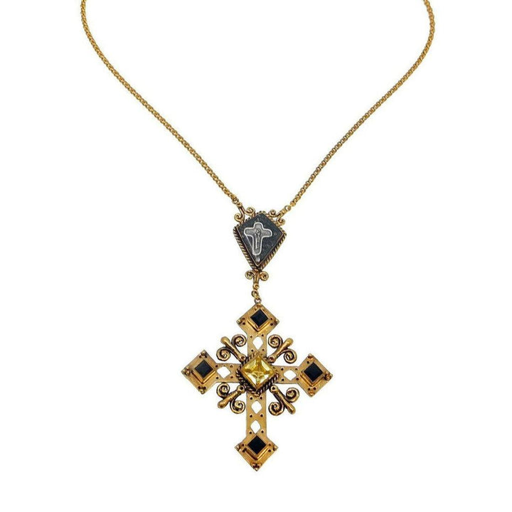 Gold cross necklace featuring black and yellow gemstones, intricate detailing, and a smaller cross pendant.