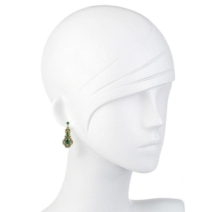 Green and gold drop earrings on a mannequin.