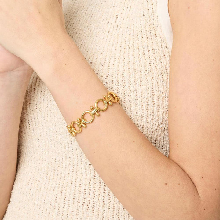 Gold link bracelet on a wrist, styled with a cream knit top.