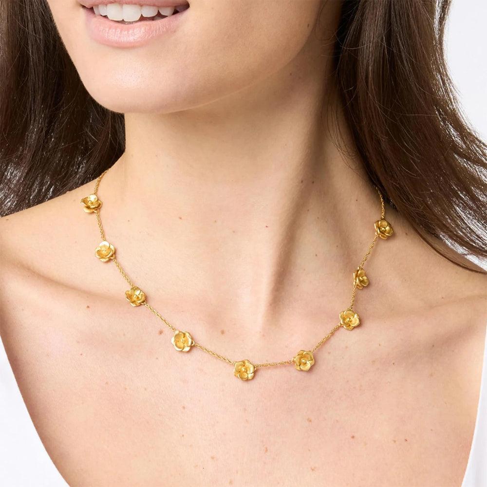 Gold necklace featuring delicate flower accents, shown on a model.