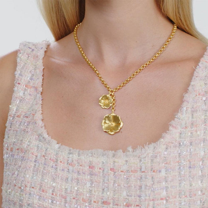 Gold lariat necklace with delicate flower pendants, shown on model.