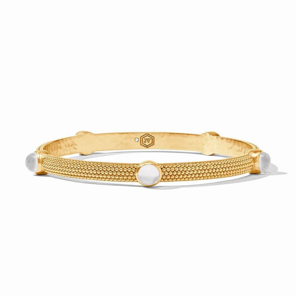 Gold bangle bracelet with textured surface and white cabochon stones.
