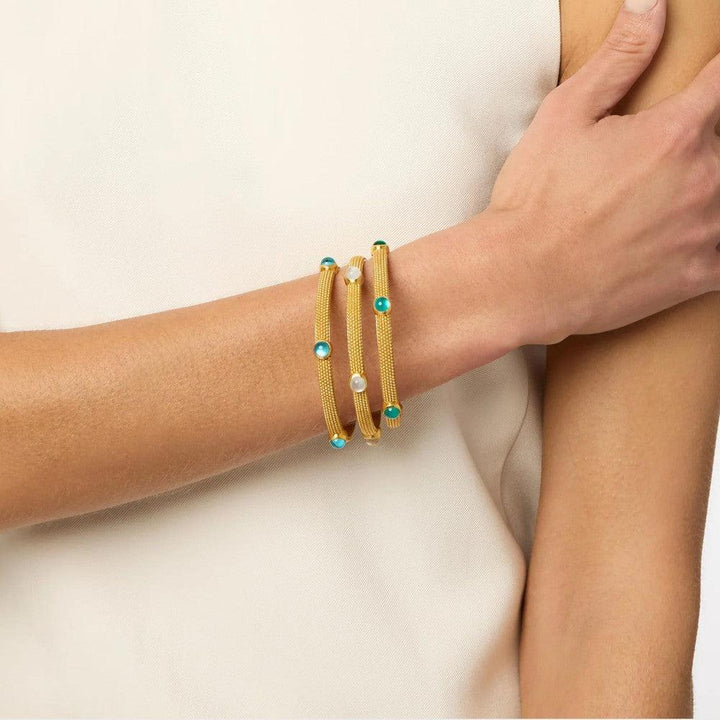 Gold mesh bangles with turquoise and pearl accents, stacked on a wrist.