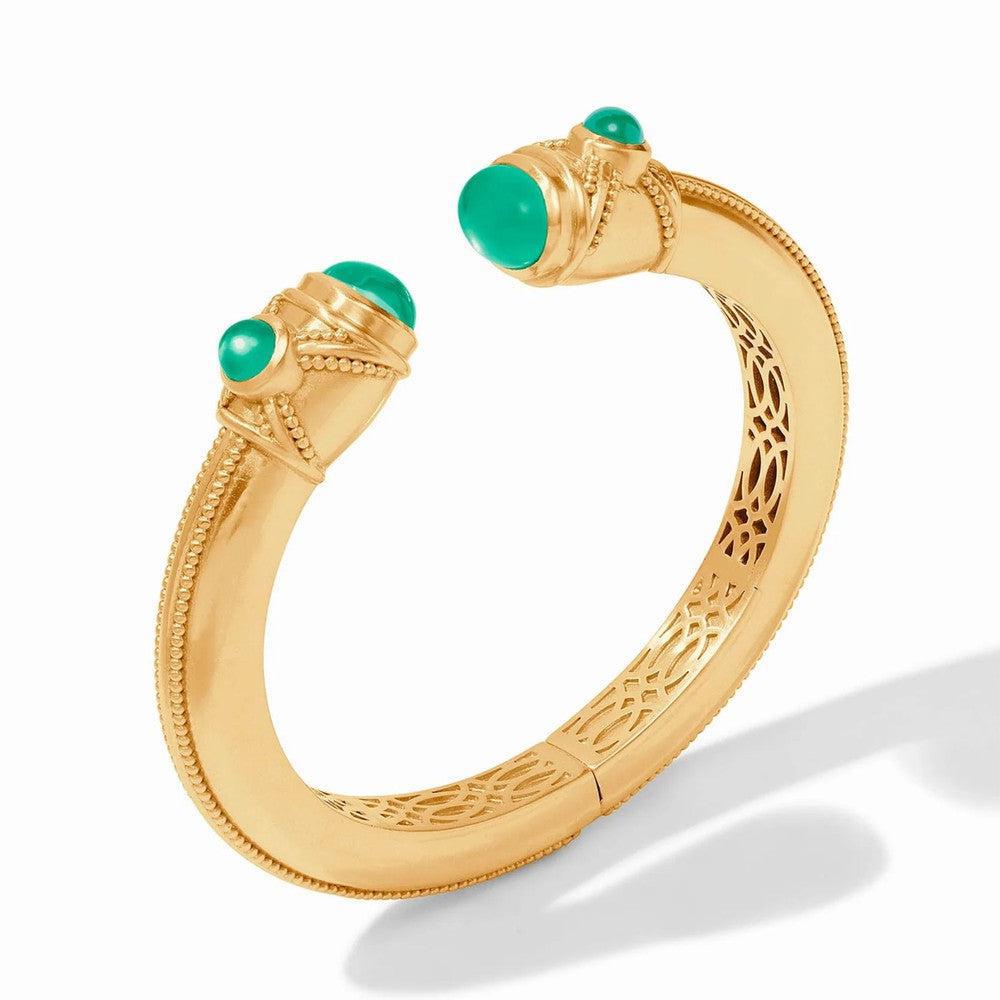 Gold cuff bracelet featuring green gemstones, intricate detailing, and a hinged design.