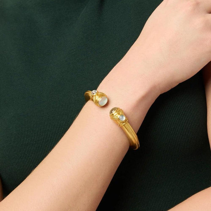 Gold cuff bracelet featuring moonstone and quartz accents on a woman's wrist.