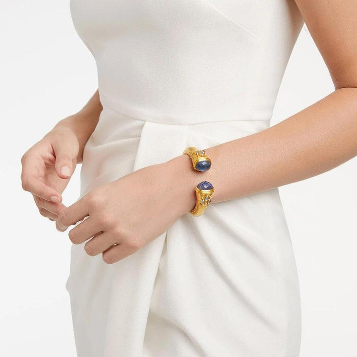 Gold hinge cuff bracelet featuring dark purple gemstones and smaller accent stones.