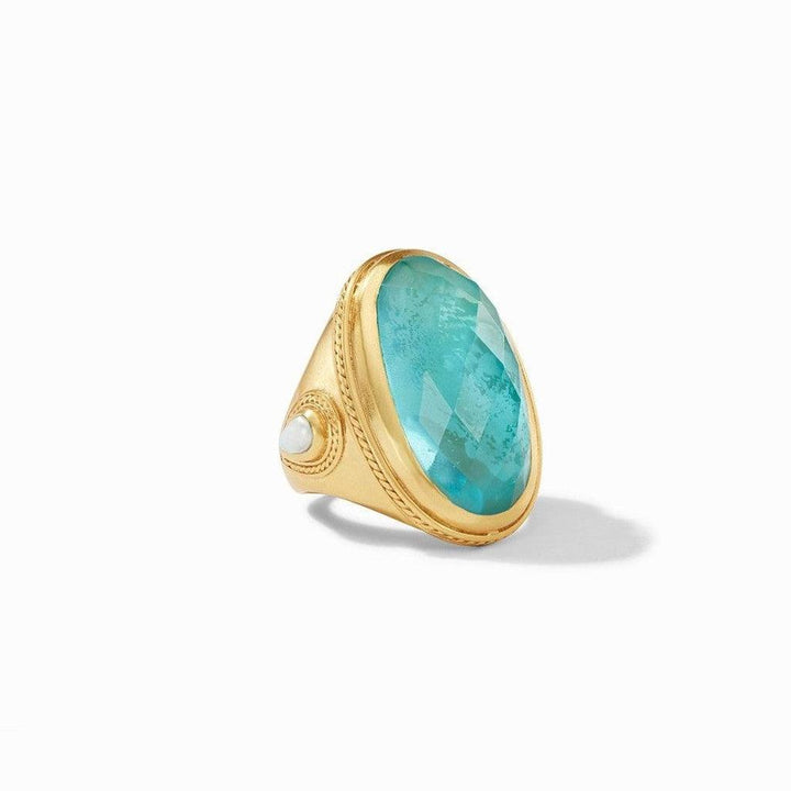 Gold statement ring featuring a large, faceted turquoise gemstone and small pearl accents.