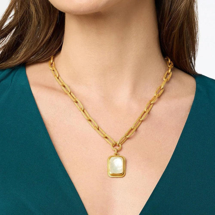 Gold chain necklace with textured links and a rectangular mother-of-pearl pendant.