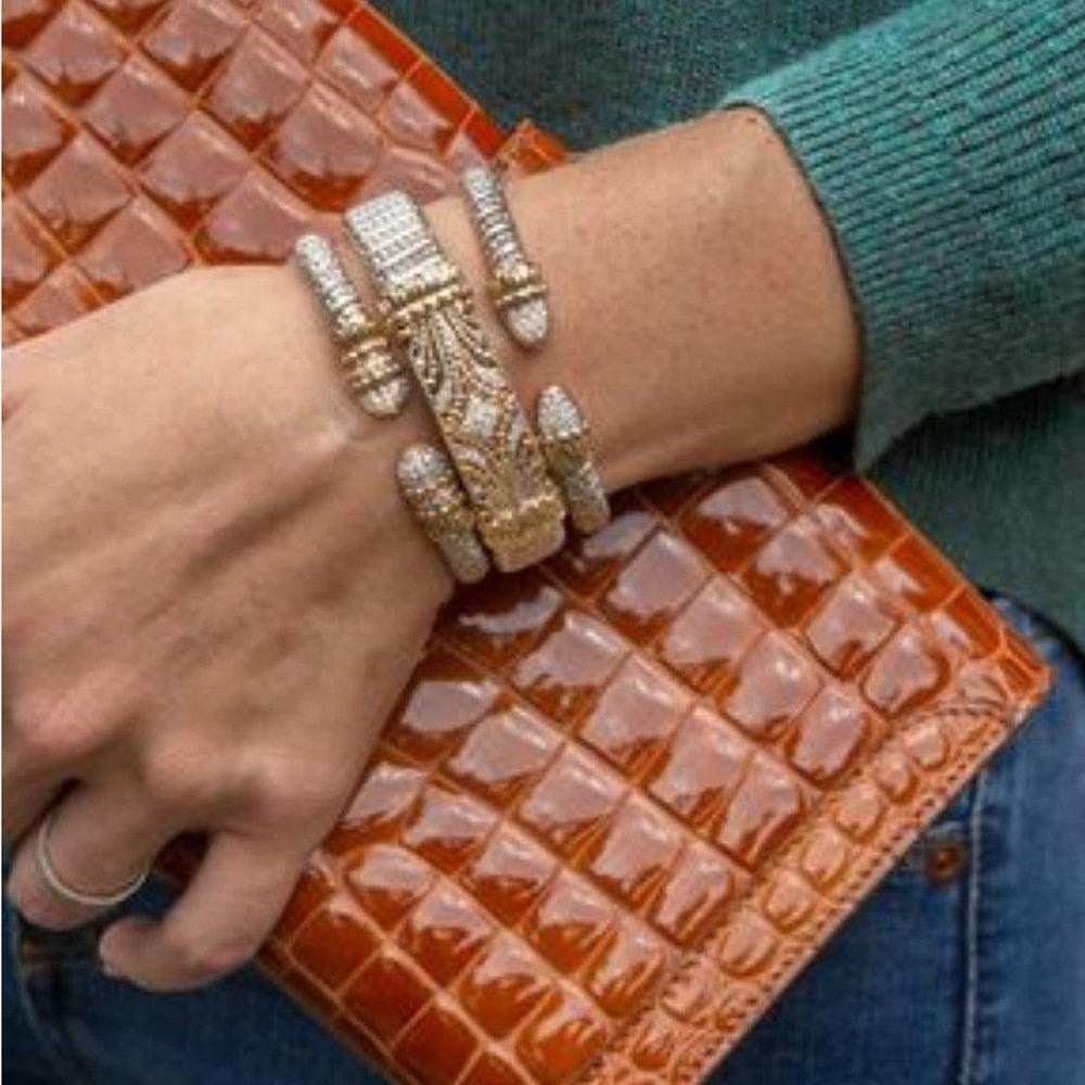 Diamond cuff bracelet, layered design, on a wrist;  shown with a brown crocodile clutch.