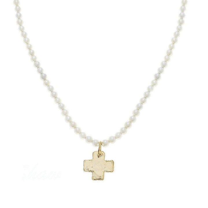 Gold cross pendant necklace on pearl strand.