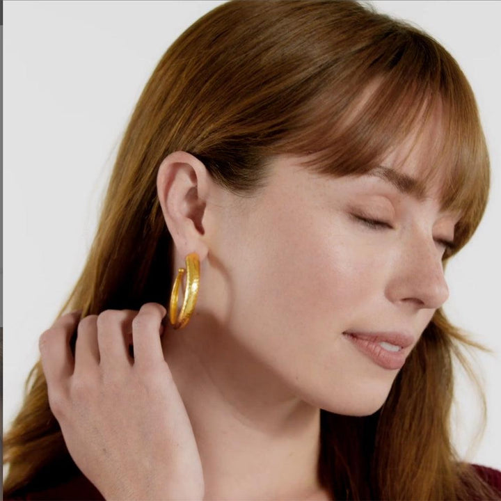 Gold hammered hoop earrings on a model.