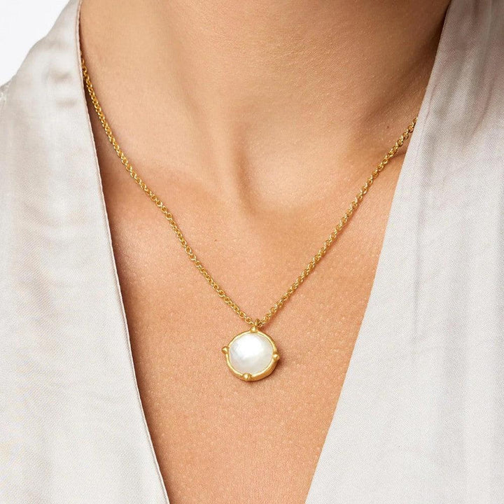 Gold chain necklace with a white gemstone pendant.
