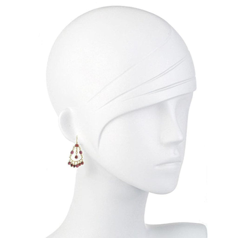 Garnet drop earrings on a mannequin, showcasing rich red gemstone accents and gold detailing.