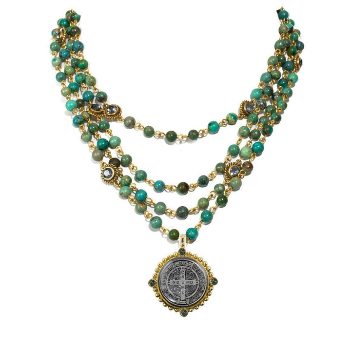 Layered turquoise and gold bead necklace with a detailed metal pendant.