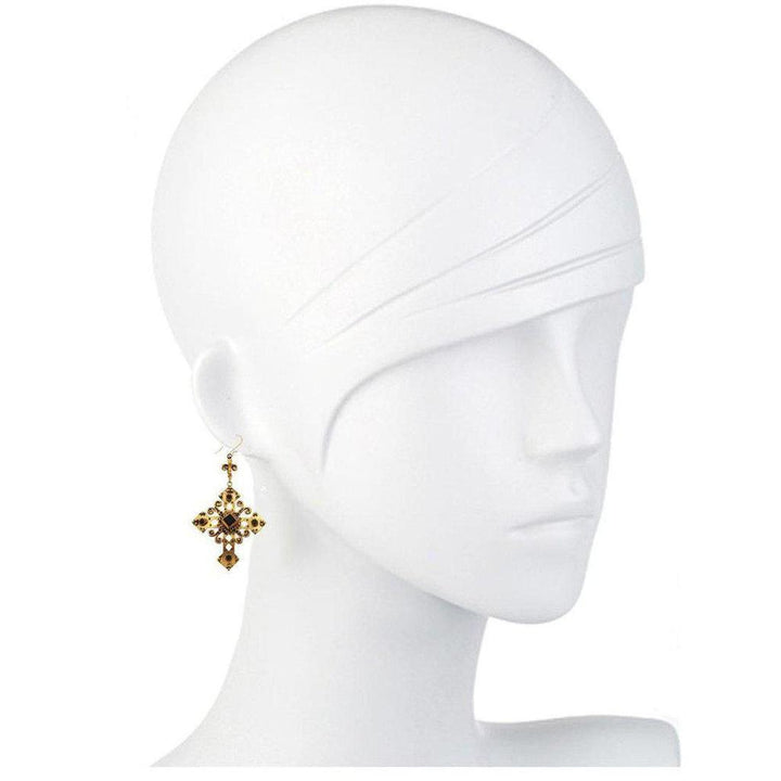 Gold cross earrings with dark amber stones, shown on a mannequin.