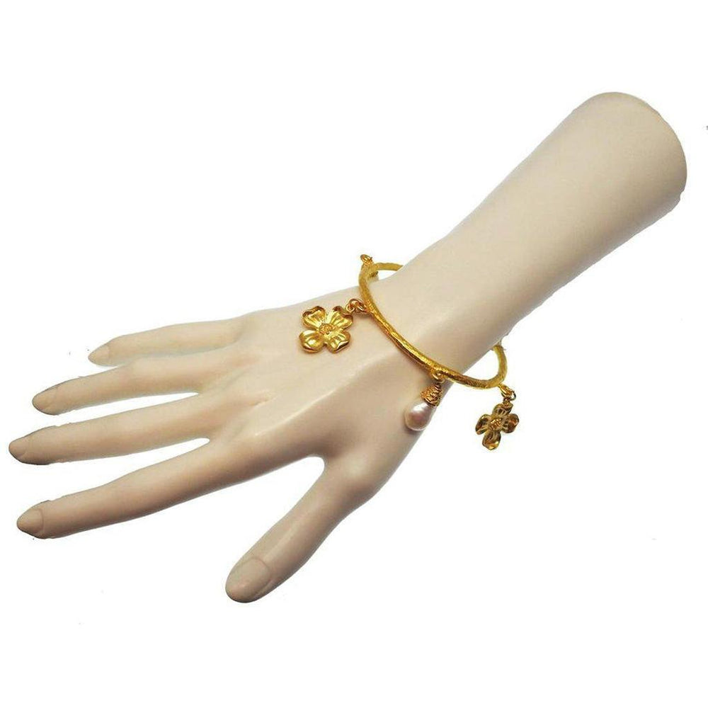 Gold bangle bracelet adorned with floral and pearl accents.