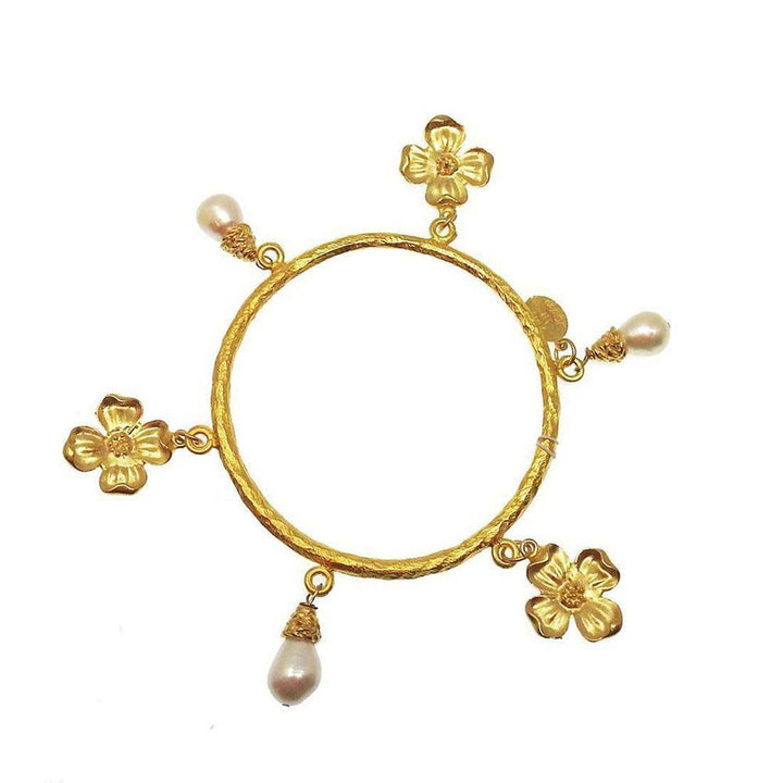 Gold bangle bracelet with three flower and pearl charms.