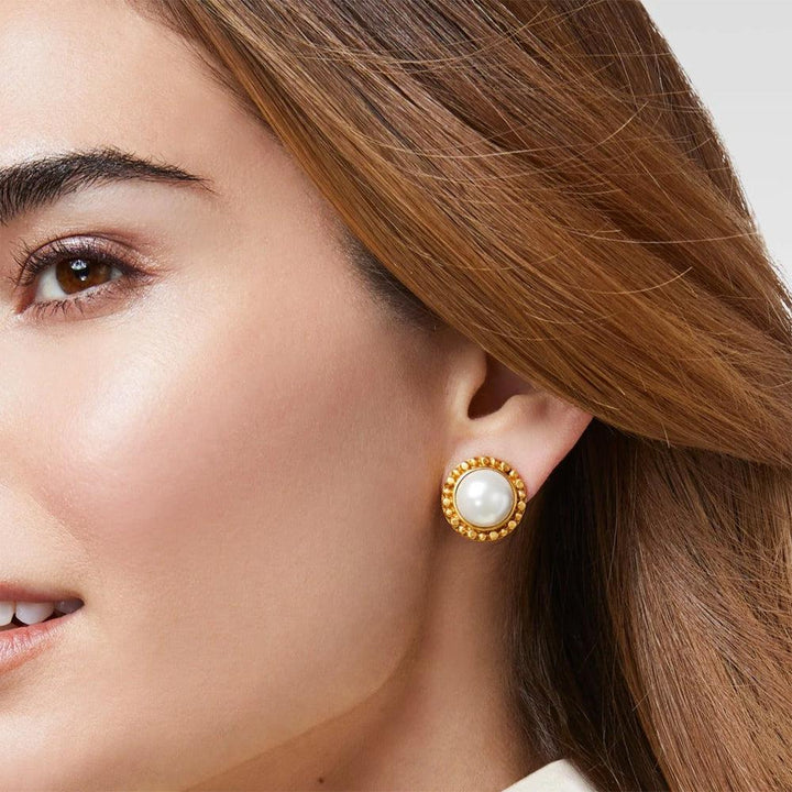 Close-up of gold beaded pearl earrings on a woman's ear.