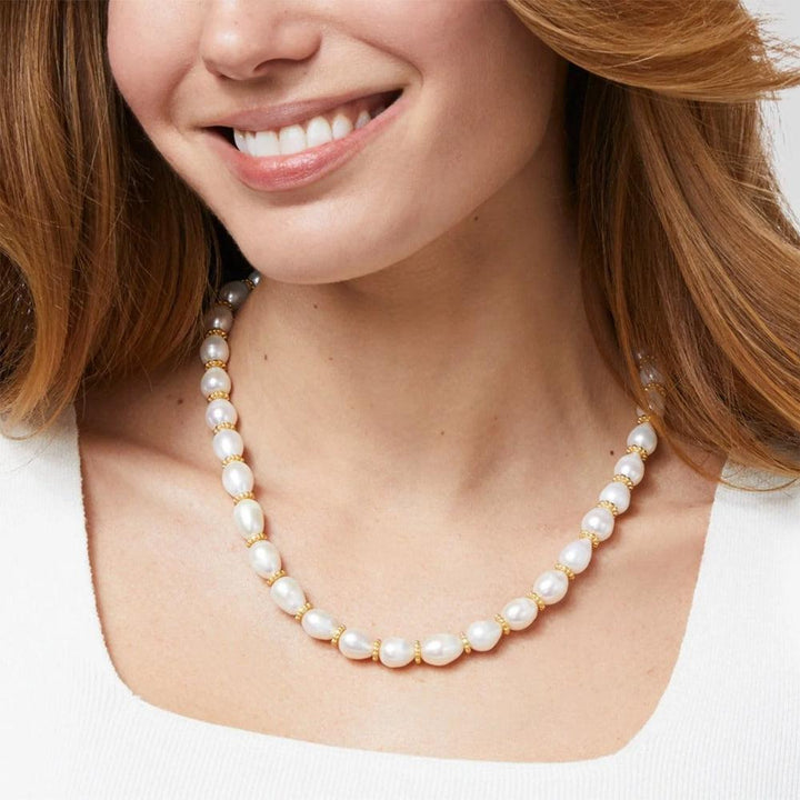 Creamy white pearl necklace with gold accents, shown on a model.